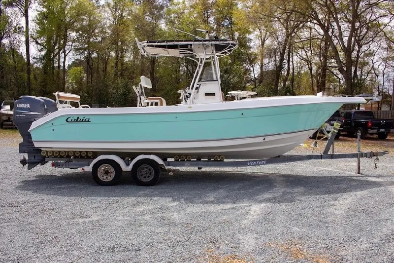 Slide: The Image of 2001 Cobia 274 Center Console boat on trailer, parked outdoors. - 2