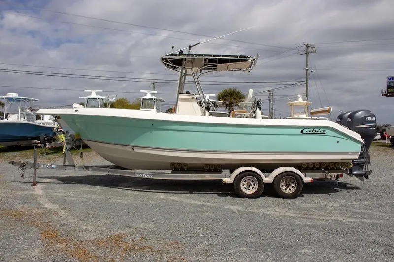 Slide: The Image of 2001 Cobia 274 Center Console boat on trailer, parked outdoors under cloudy sky. - 3