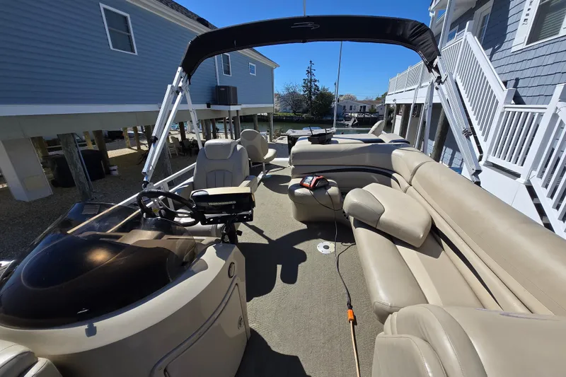 Slide: The Image of 2013 Bennington 2574 GL pontoon boat with beige seating and canopy, docked near waterfront homes. - 11