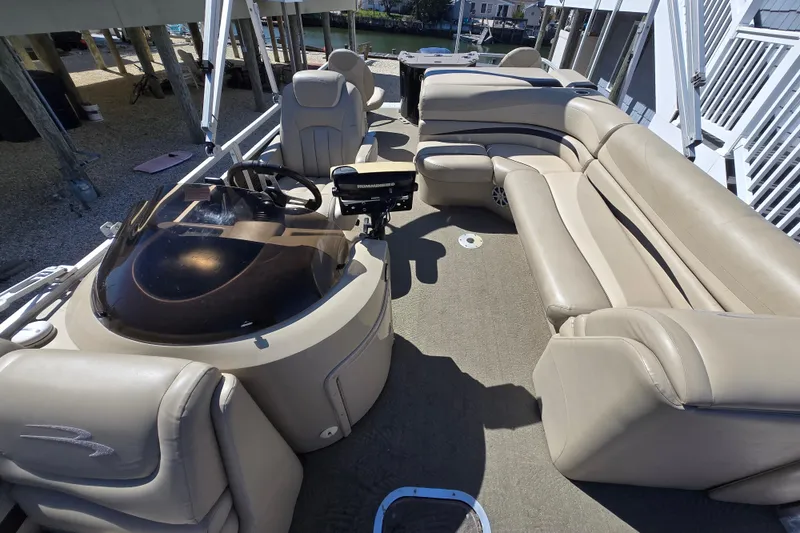 Slide: The Image of 2013 Bennington 2574 GL pontoon boat interior with beige seating and steering console. - 16