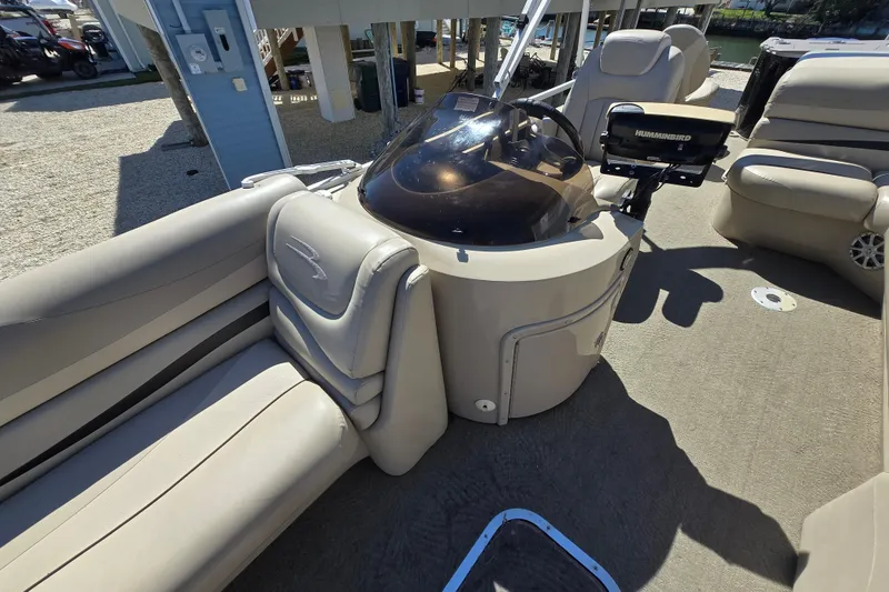 Slide: The Image of 2013 Bennington 2574 GL pontoon boat interior with beige seating and control console. - 17