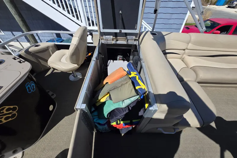 Slide: The Image of 2013 Bennington 2574 GL pontoon boat interior with open storage compartment and life jackets. - 27