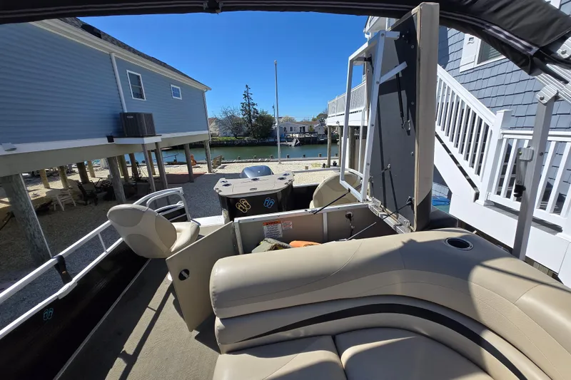 Slide: The Image of 2013 Bennington 2574 GL pontoon boat interior near waterfront homes. - 29