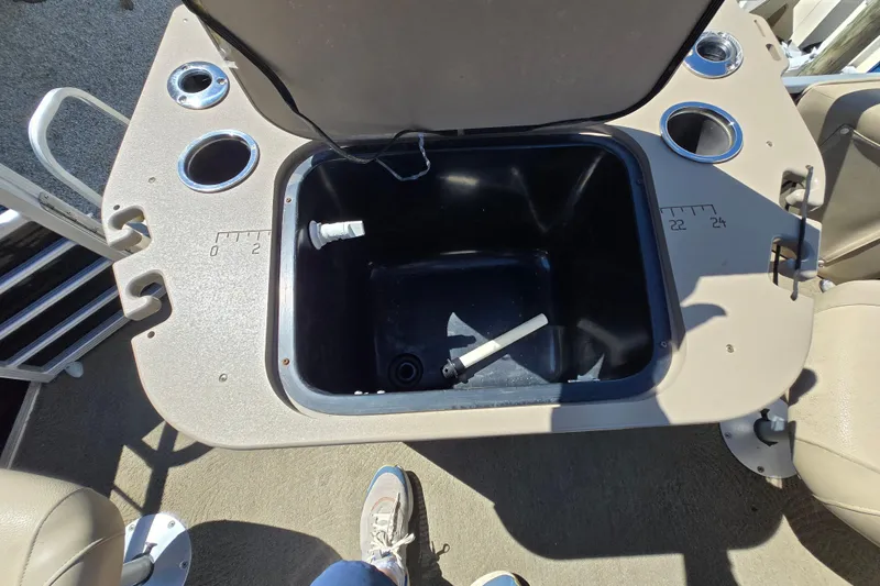 Slide: The Image of 2013 Bennington 2574 GL boat interior with open storage compartment and cup holders. - 31