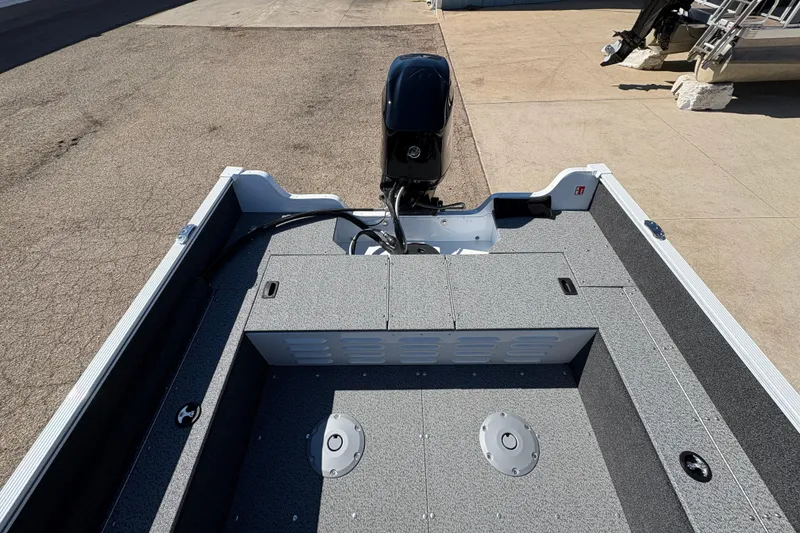 Slide: The Image of 2026 Lund 1650 Angler SS boat interior with motor, showcasing spacious deck and storage compartments. - 16