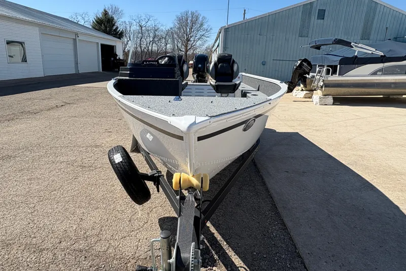 Slide: The Image of 2026 Lund 1650 Angler SS boat on trailer, parked outdoors near buildings. - 6