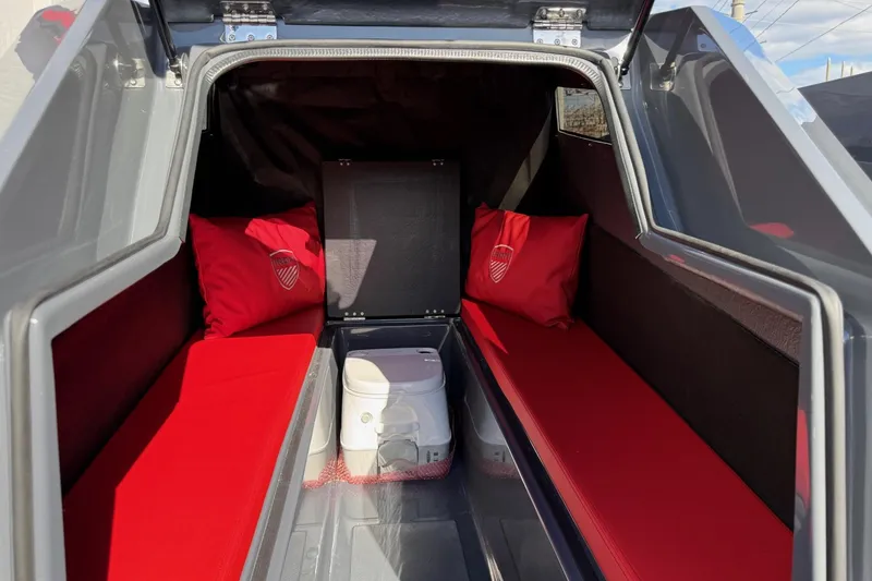 Slide: The Image of Interior of 2026 Iron 907 camper with red cushions and portable toilet. - 12