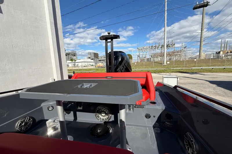 Slide: The Image of 2026 Iron 907 boat interior with red seating, table, and visible engine, outdoors. - 15
