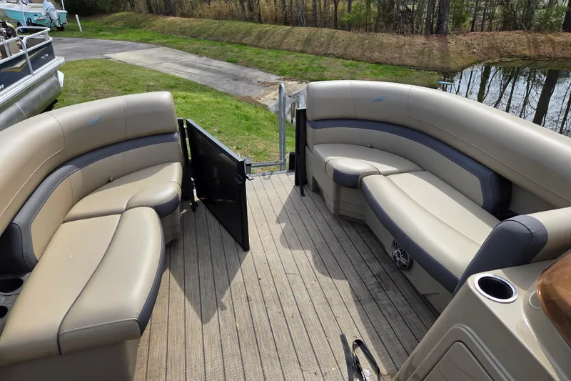 Slide: The Image of 2024 Starcraft EXS 1 pontoon boat interior with beige seating and open gate. - 8