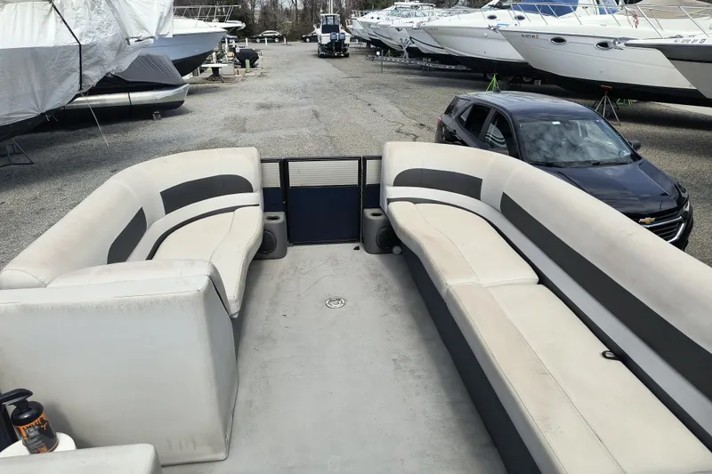 Slide: The Image of 2018 Crest I Fish 220 C4 pontoon boat with spacious seating, parked near other boats. - 10