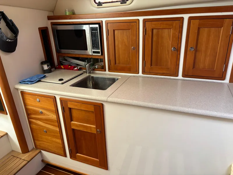 Slide: The Image of 2006 MJM 34z Express HT yacht kitchen with wooden cabinets, sink, and microwave. - 31