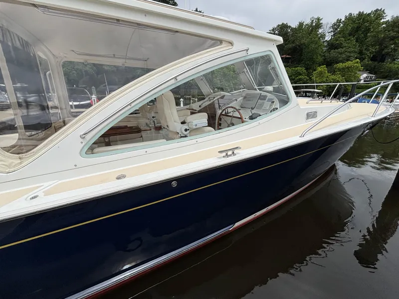 Slide: The Image of 2006 MJM 34z Express HT boat docked on calm water, showcasing sleek design and spacious interior. - 4