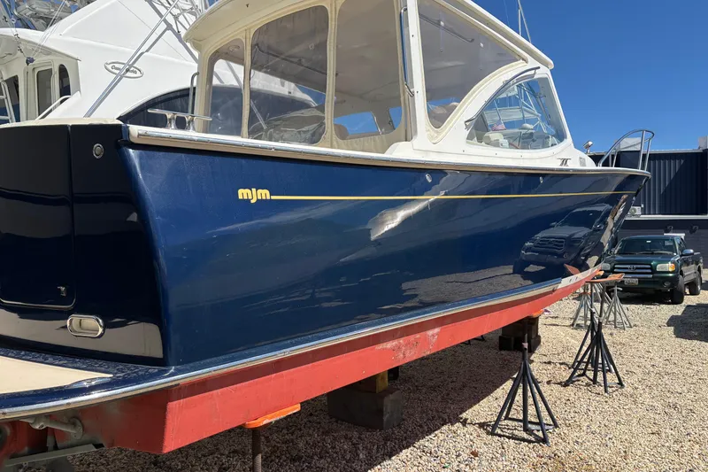 Slide: The Image of 2006 MJM 34z Express HT boat on stands, blue hull, sunny day. - 5