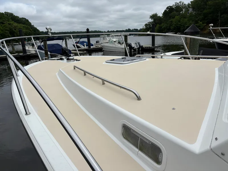 Slide: The Image of 2006 MJM 34z Express HT boat docked at a marina, featuring a spacious deck. - 9