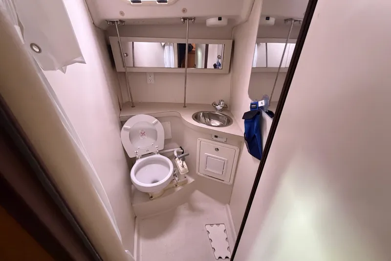 Slide: The Image of Compact bathroom in a 2007 Catalina 309 sailboat, featuring a toilet, sink, and mirror. - 11