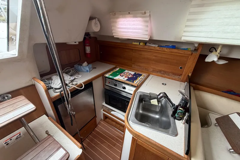 Slide: The Image of Compact kitchen area in a 2007 Catalina 309 sailboat with stove, sink, and storage. - 17