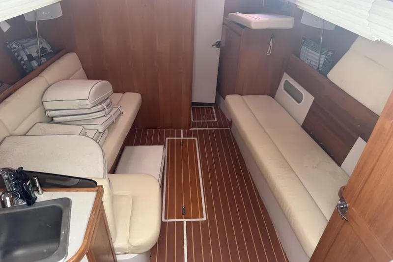 Slide: The Image of Interior of 2007 Catalina 309 sailboat with wooden flooring and beige seating. - 24