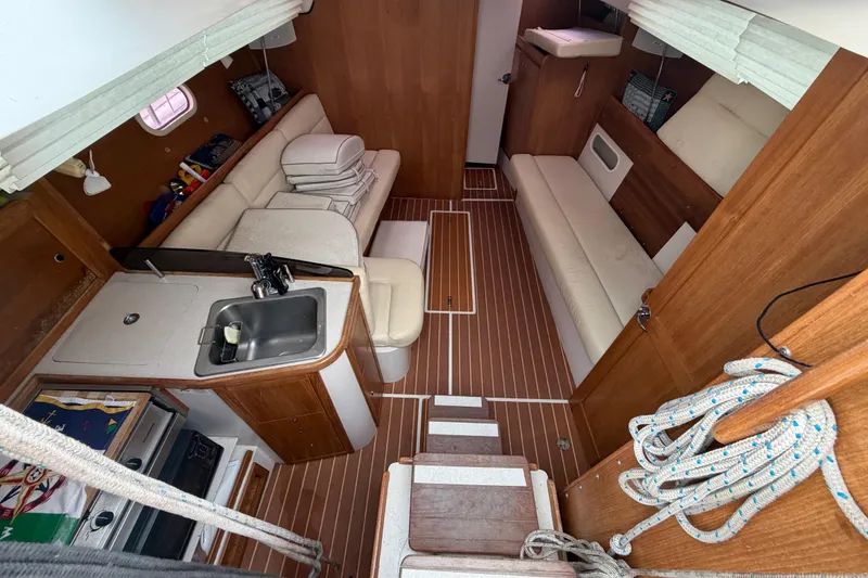 Slide: The Image of Interior of a 2007 Catalina 309 sailboat, featuring a cozy cabin with seating and kitchenette. - 25