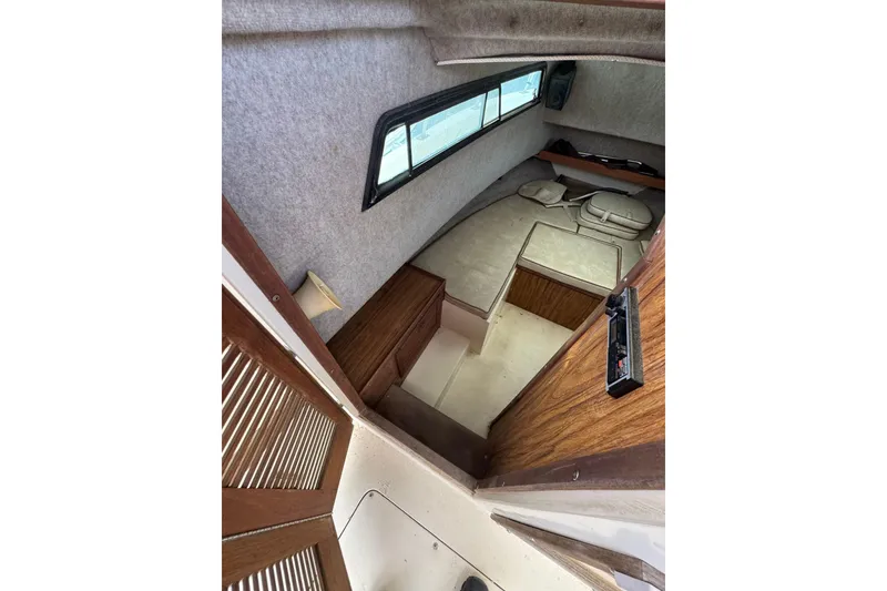 Slide: The Image of Interior cabin of 1987 Mako 230 Walk Around boat with wood accents and seating area. - 10
