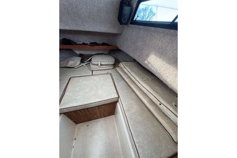Slide: The Image of Interior cabin of 1987 Mako 230 Walk Around boat, featuring cushioned seating and storage. - 12