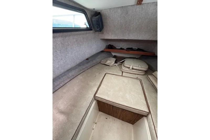 Slide: The Image of Interior cabin of a 1987 Mako 230 Walk Around boat, featuring cushioned seating. - 13