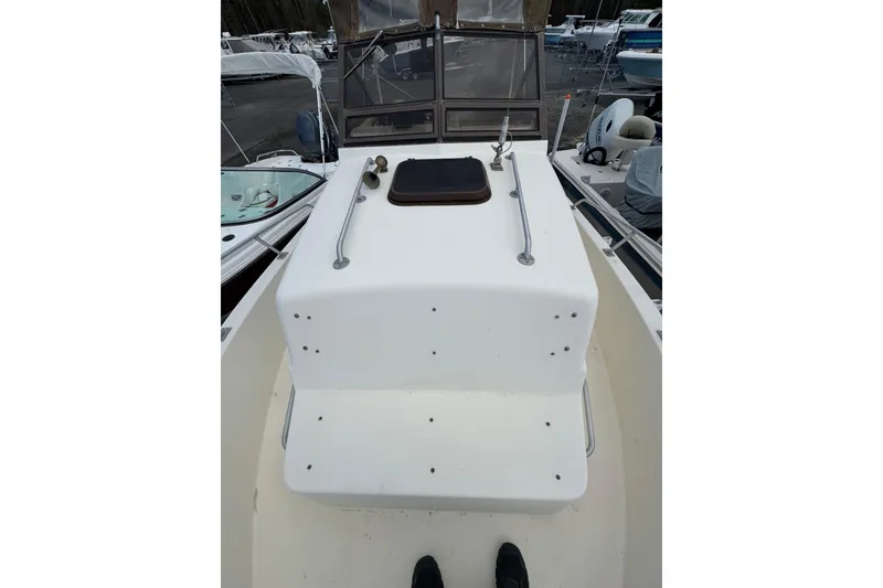 Slide: The Image of 1987 Mako 230 Walk Around boat deck with railing and hatch, docked among other boats. - 15