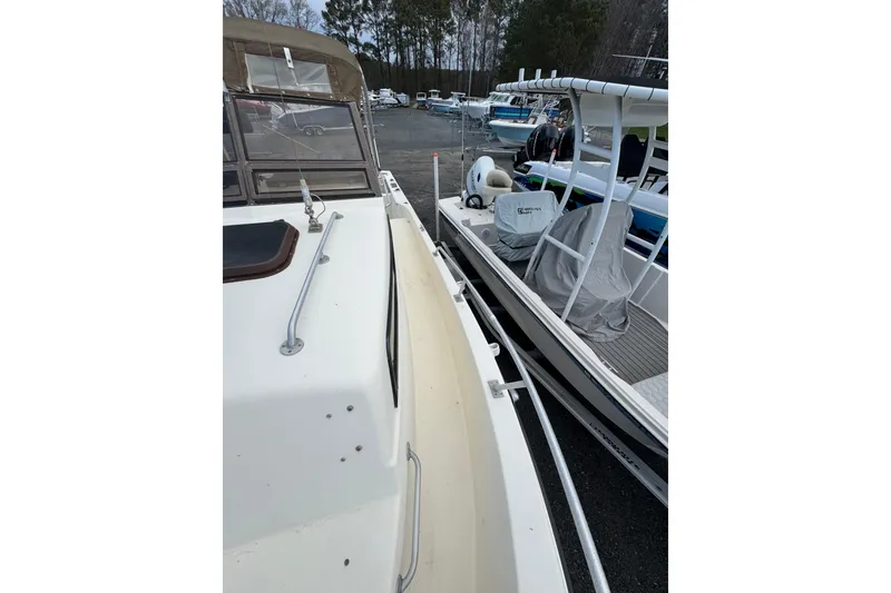 Slide: The Image of 1987 Mako 230 Walk Around boat docked beside another vessel in a marina. - 16