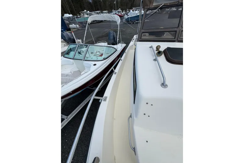 Slide: The Image of 1987 Mako 230 Walk Around boat docked beside another vessel in a marina. - 17