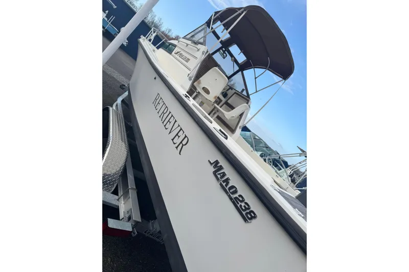 Slide: The Image of 1987 Mako 230 Walk Around boat with canopy, named "Retriever," on a trailer. - 2