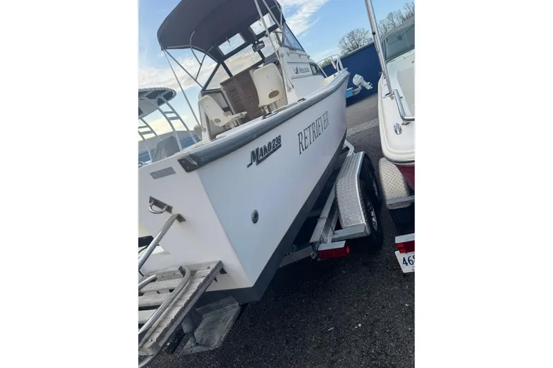 Slide: The Image of 1987 Mako 230 Walk Around boat on trailer, named "Retriever," parked outdoors. - 3
