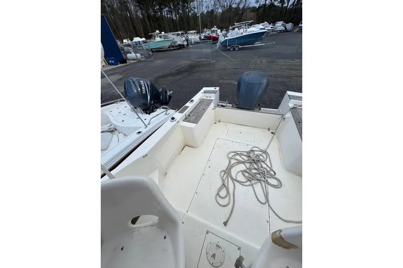 Slide: The Image of 1987 Mako 230 Walk Around boat with outboard motor in a marina setting. - 7