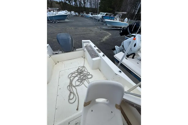 Slide: The Image of 1987 Mako 230 Walk Around boat interior with coiled rope, parked among other boats. - 8