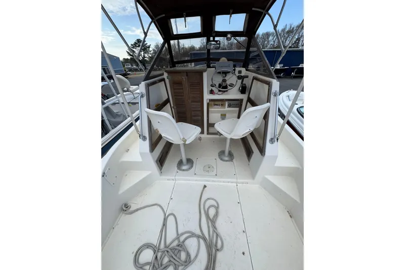 Slide: The Image of 1987 Mako 230 Walk Around boat interior with helm, seats, and coiled rope. - 9