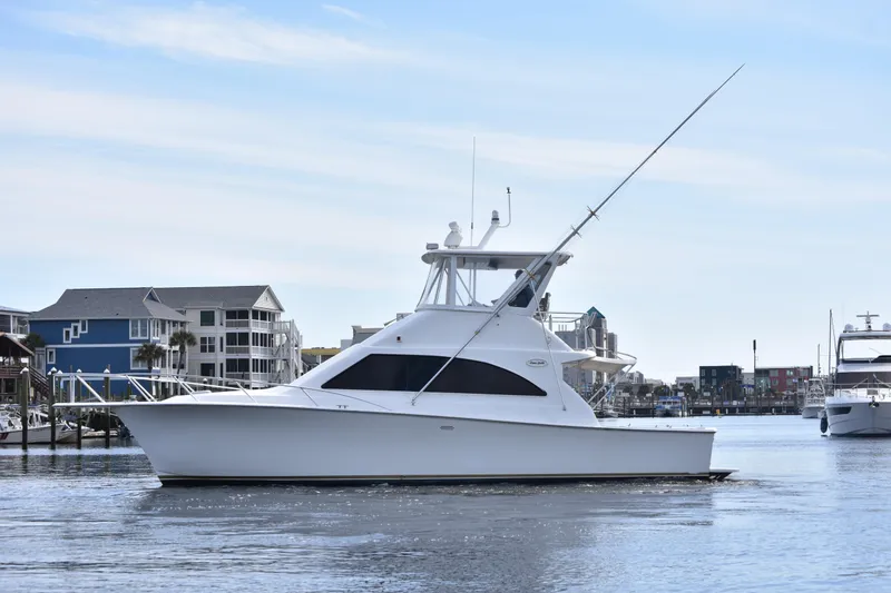 The Image of 1998 Ocean Yachts 40 Super Sport boat docked in a marina with waterfront buildings. - 0