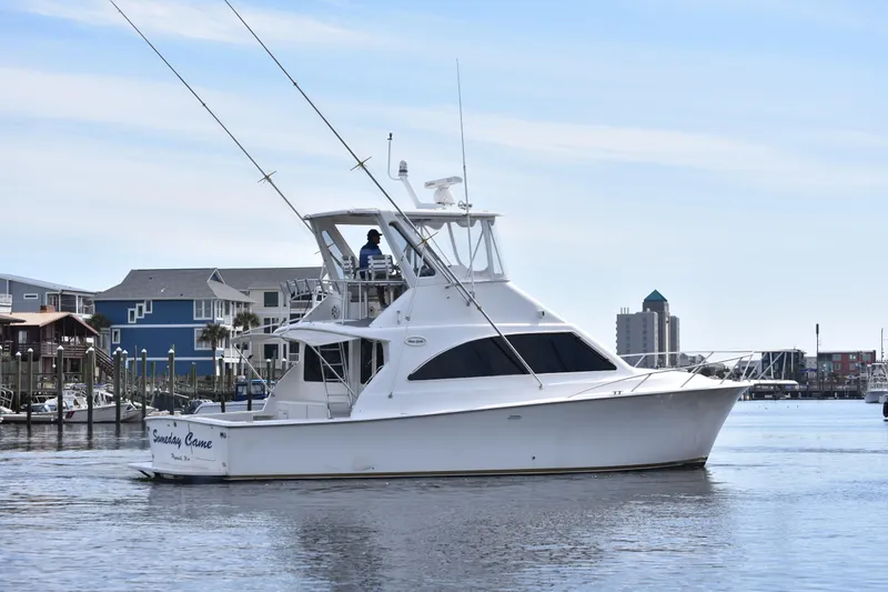 Slide: The Image of 1998 Ocean Yachts 40 Super Sport cruising in a marina with coastal buildings in the background. - 1