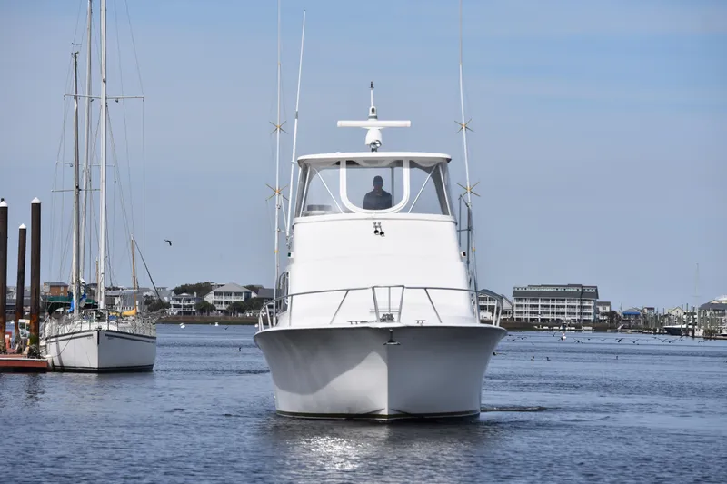 Slide: The Image of 1998 Ocean Yachts 40 Super Sport cruising in a marina with sailboats and buildings in the background. - 10