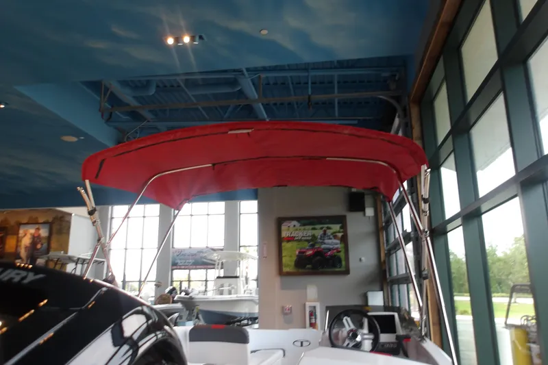 Slide: The Image of 2026 Tahoe T16 boat with red canopy displayed indoors. - 13
