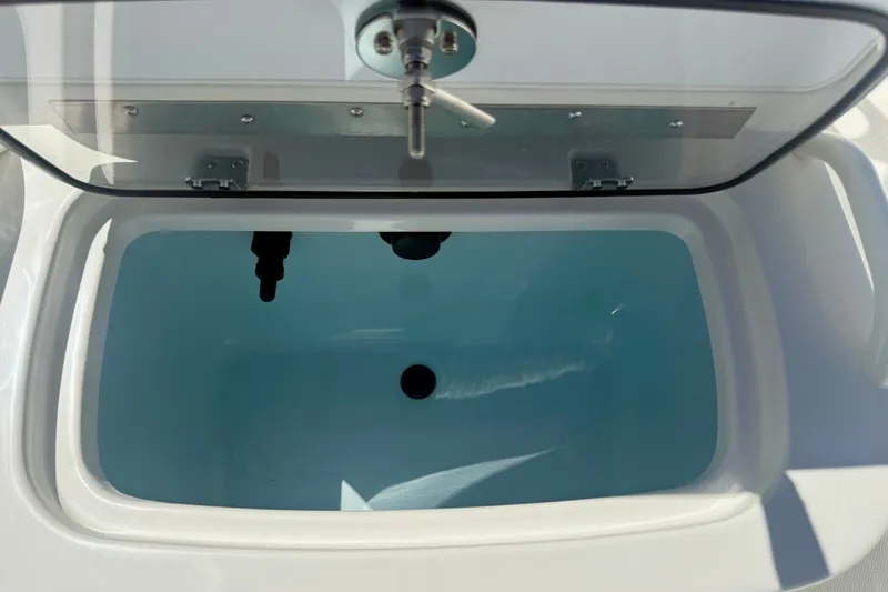 Slide: The Image of Livewell compartment on a 2026 Mako Pro Skiff 19 CC boat, open lid view. - 13