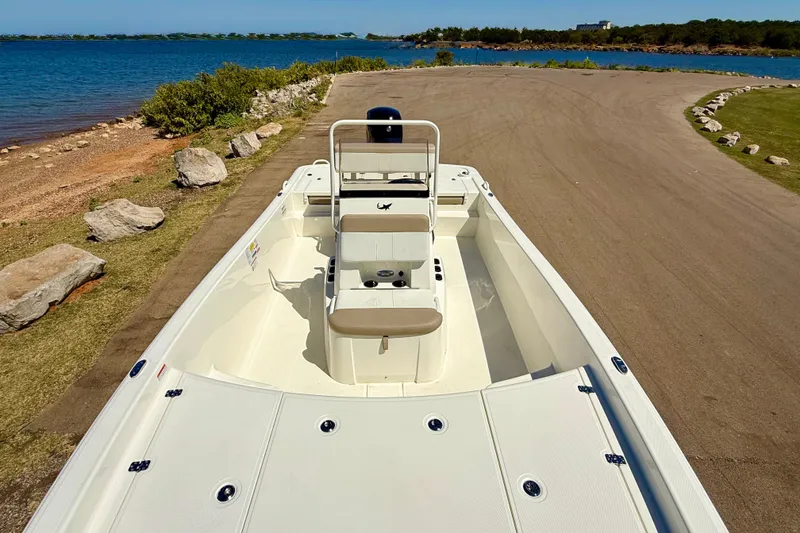 Slide: The Image of 2026 Mako Pro Skiff 19 CC boat on a lakeside ramp, ready for launch. - 19
