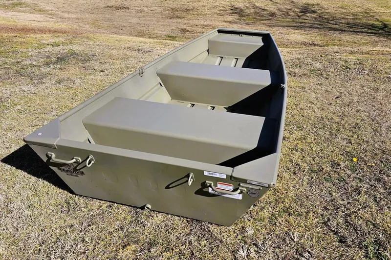 Slide: The Image of 2026 Tracker Grizzly 12 Jon boat on grassy terrain, showcasing durable design and spacious interior. - 7