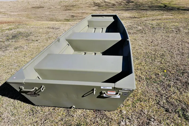 Slide: The Image of 2026 Tracker Grizzly 12 Jon boat on grassy terrain, showcasing durable design and seating. - 6