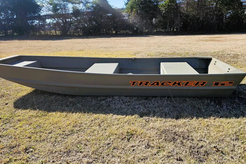 Slide: The Image of 2026 Tracker Grizzly 12 Jon boat on grassy field, side view. - 2