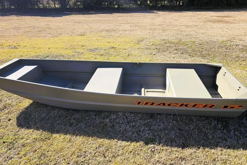 Slide: The Image of 2026 Tracker Grizzly 12 Jon boat on grassy field, showcasing durable design. - 3