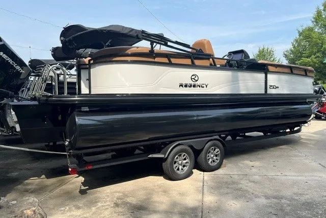 The Image of 2026 Regency 250 DL pontoon boat on trailer, parked outdoors. - 0