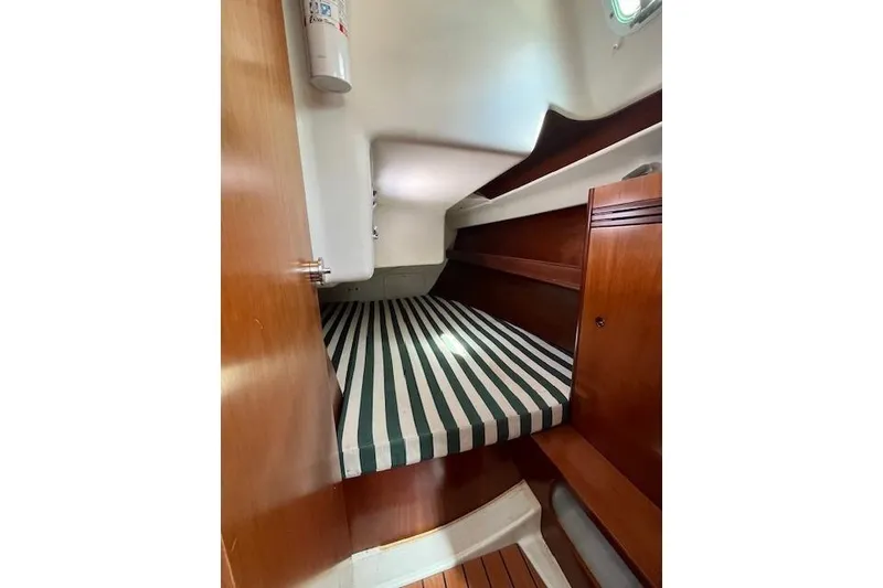 Slide: The Image of Cabin interior of 2005 Beneteau First 36.7 with striped bedding and wooden finishes. - 36
