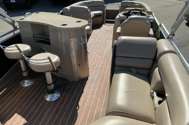 Slide: The Image of 2015 Berkshire 230E STS pontoon boat interior with beige seating and bar area. - 10