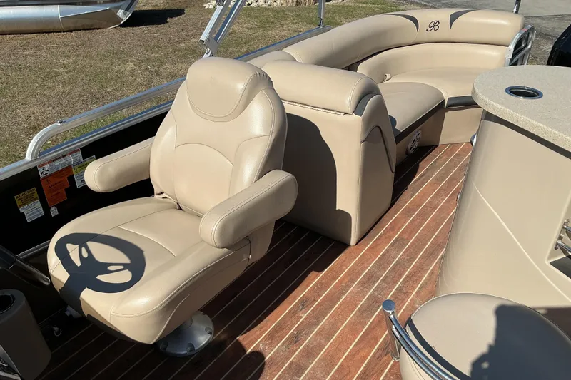 Slide: The Image of 2015 Berkshire 230E STS pontoon boat interior with beige seating and wood-style flooring. - 11
