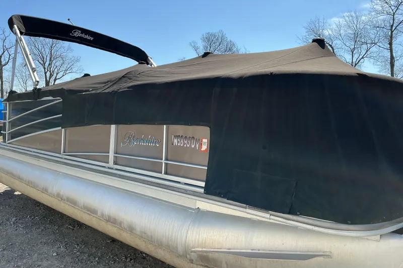 Slide: The Image of 2015 Berkshire 230E STS pontoon boat covered, parked outdoors. - 16