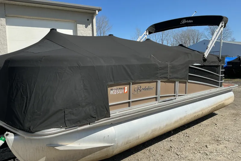 Slide: The Image of 2015 Berkshire 230E STS pontoon boat with black cover, parked outdoors. - 17