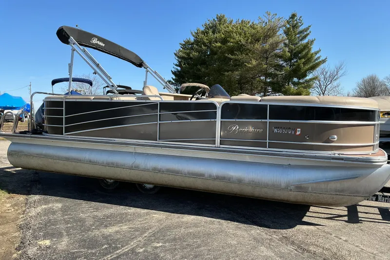 Slide: The Image of 2015 Berkshire 230E STS pontoon boat parked on pavement, featuring sleek design and canopy. - 3